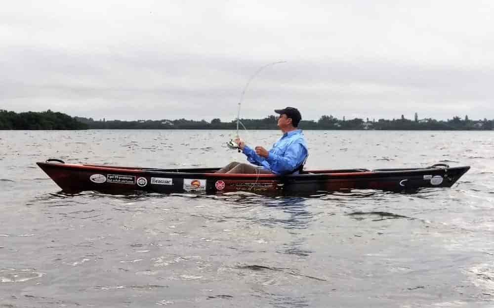 man in racing canoe casting a bait casting rod and reel fishing
