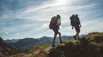 couple hiking up narrow trail on top of mountain