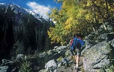man walking alone up trail mountains in background