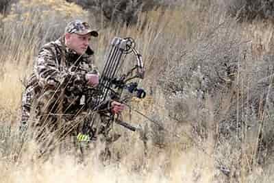 hunter kneeling down with compound bow in hand