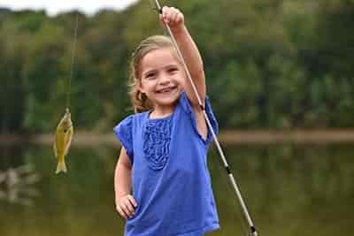 New Jersey little girl holding up her first fish catch smiling with missing teeth
