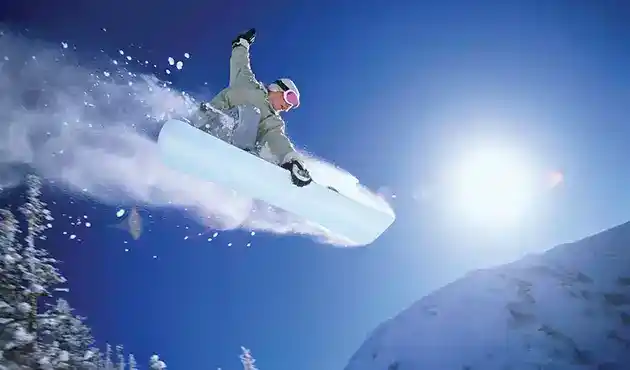 snowboarder plowing snow off jump
