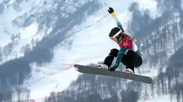 woman snowboarder flying in air holding edge of snowboard