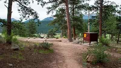 rocky mountain background with empty camping spot and large trash protection container