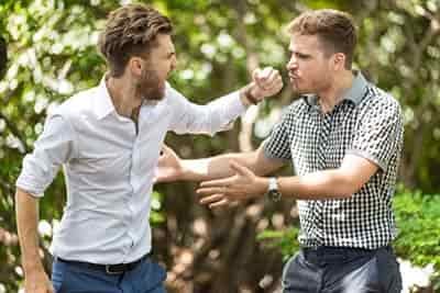 2 men about to fight agueing while one man throws punch