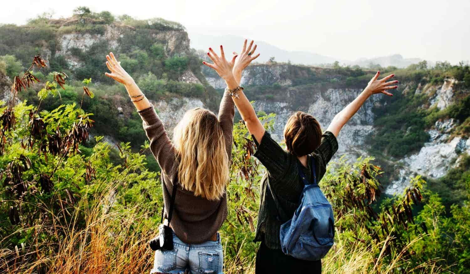two college girls arms in the air celebrating the outdoors