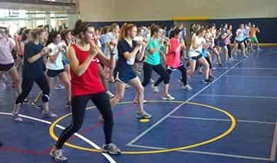 50 college women training in self_defense in lines and organized at a college gym