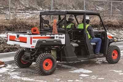 construction workers 2 men riding around job site in a bobcat utv