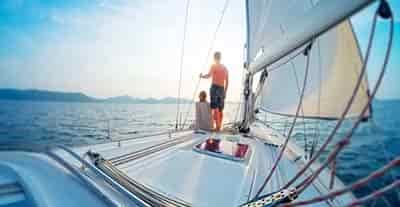couple standing on front of sail boat at sunset