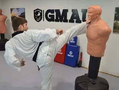 young man kicking practice dummy for higher kicks and strength