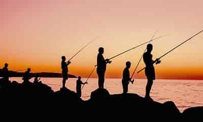 8 people fishing from large rocky shore line at sunrise