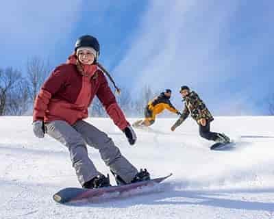 3 women Snowboarders following each other down slope