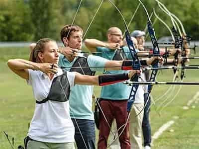 5 archers lined up all using recurve bow aiming at target arrow