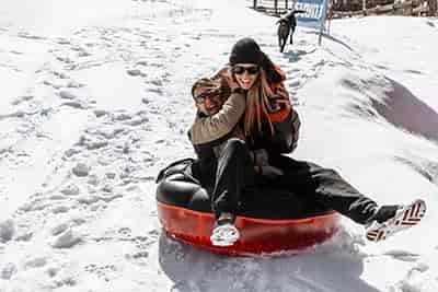 couple snow tubing laughing