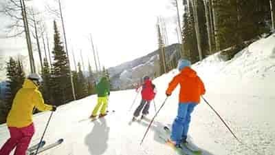 four skiiers mother father and 2 girls skiing down easy path
