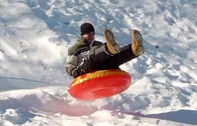 man riding and jump on inner tube snowing
