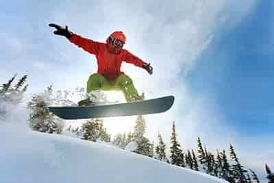 Snowboarder jumping wearing helmet and googles