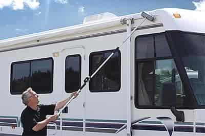 man washing an rv with extension brush