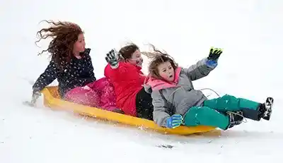 three young girls having fun sledding