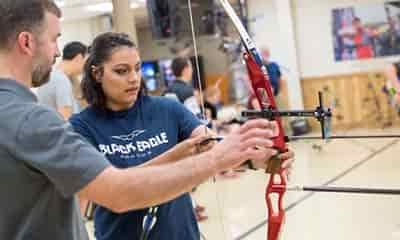 woman taking direction from expert archer with recurve bow