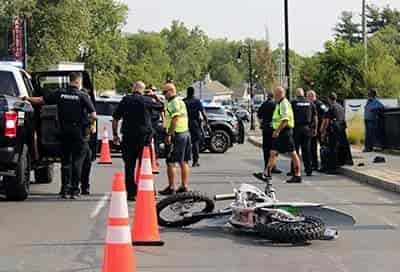 wreck envolving dirt bike on street rider on curb surrounded by police