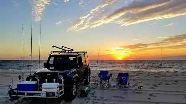 sun rising day break surf fishing complete with vehicle coolers and fishing gear