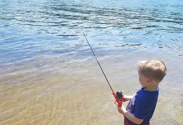 small boy fishing in river road campgrounds lake