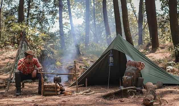 man sipping drink while camping