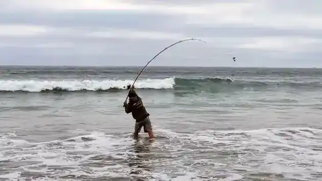 man surf fishing casting